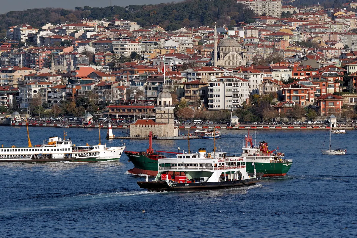 Maiden's Tower on its small islet off the Asian shore, with ferries and cargo ships crossing the blue water in front of Üsküdar.