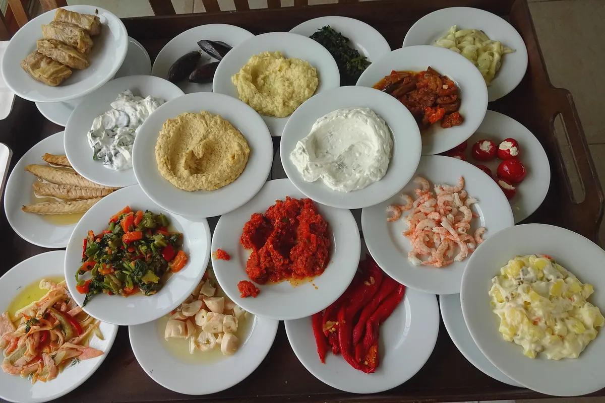 A tray of small round plates of meze, with dips, salads, stuffed vegetables and seafood, at a restaurant.
